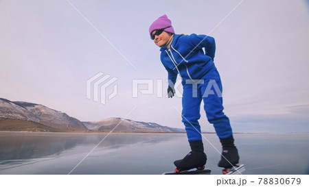 The child train on ice professional speed skating. The girl skates in the winter in sportswear, sport glasses, suit. Outdoor slow motion. 78830679