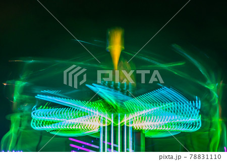 A blurry colorful carousel in motion at the amusement park, night illumination. Long exposure. 78831110