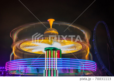 A blurry colorful carousel in motion at the amusement park, night illumination. Long exposure. 78831113