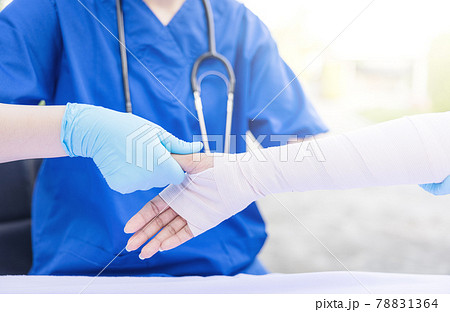 Close-up of female doctor putting a bandage on injured hand upper limb of patient. 78831364