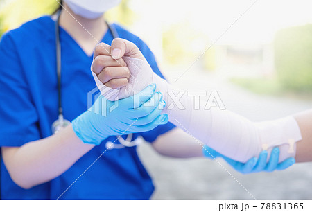 Close-up of female doctor putting a bandage on injured hand upper limb of patient. 78831365