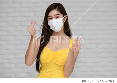 Wellness asian young woman wear face mask and yellow camisole make mini heart for good protection and vaccine happiness and cheerful,New normal due virus pandemic concept 78832963