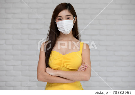 Wellness asian young woman wear face mask and yellow camisole cross arm confident for good protection and vaccine happiness and cheerful,New normal due virus pandemic concept 78832965
