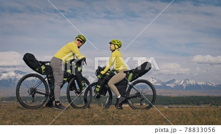 The man and woman travel on mixed terrain cycle touring with bikepacking. The love couple journey with tent in with bicycle bags. Stylish sportswear. 78833056