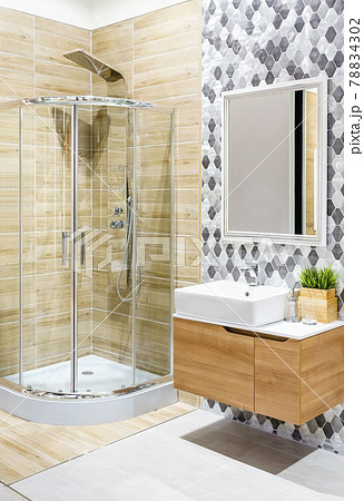 Spacious and bright modern bathroom interior with white walls, a shower cabin with glass wall, a toilet and faucet sink 78834302