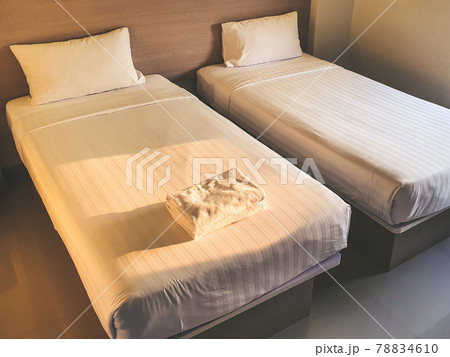 Clean white towel on white clean bedroom in the budget hotel for traveller with sunset light from the window Clean white towel on white clean bedroom in the budget hotel for traveller with sunset light from the window 78834610