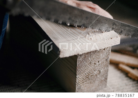 Man in the workshop with a wood and saw Man in the workshop with a wood and saw 78835167