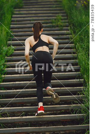 Woman in a black spoerswear standing on a stairs 78835439
