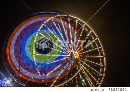 Ferris wheel in motion at the amusement park, night illumination. Long exposure Ferris wheel in motion at the amusement park, night illumination. Long exposure 78835842