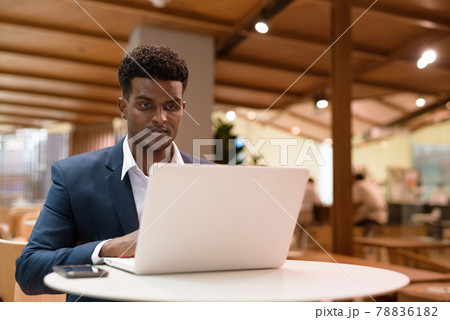 Portrait of African businessman using laptop computer in coffee shop 78836182