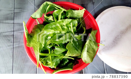 Fresh spinach leaves in red bowl on wooden background 78837390