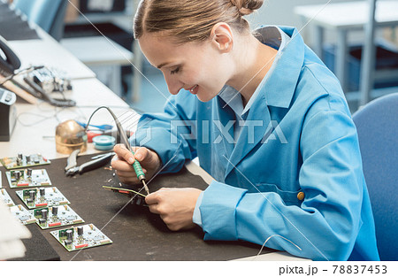 Worker in electronics manufacturing soldering a component 78837453