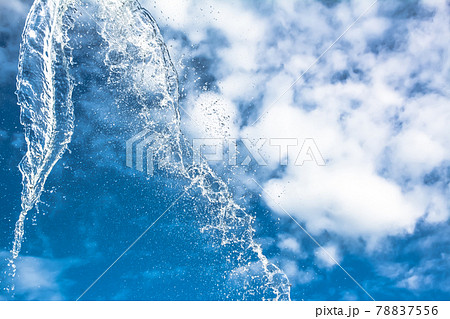Splashes of water against a blue sky with clouds. A splash of water against the sky. 78837556