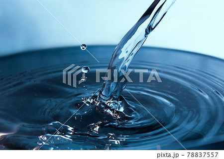 Blue stream of water on a light background. Water pouring into a large bowl. 78837557