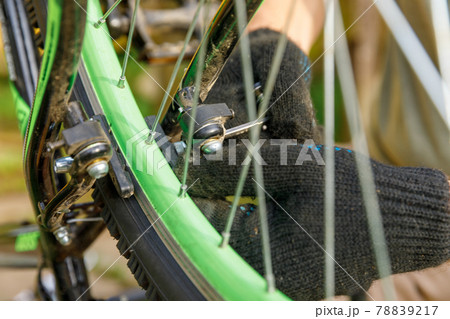 Bike mechanic man repairs bicycle in bicycle repair shop, outdoor. Hand of cyclist bicyclist examines, fixes modern cycle transmission system. Bike maintenance, sport shop concept. 78839217
