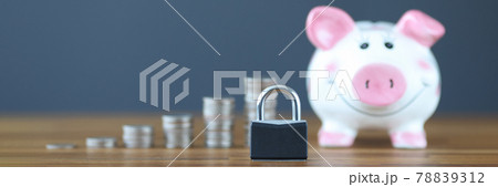 Padlock standing on background of piggy bank and coins closeup 78839312