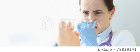 Doctor dermatologist holding patients foot and covering nose with hand 78839341