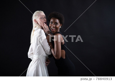 Caucasian and african american young woman isolated on black background. 78840913