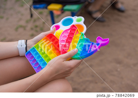 Colorful antistress sensory toy fidget push pop it in toddler's hands. Antistress trendy pop it toy. Rainbow sensory fidget. New trendy silicone toy. dolphin shape Colorful antistress sensory toy fidget push pop it in toddler's hands. Antistress trendy pop it toy. Rainbow sensory fidget. New trendy silicone toy. dolphin shape 78842069
