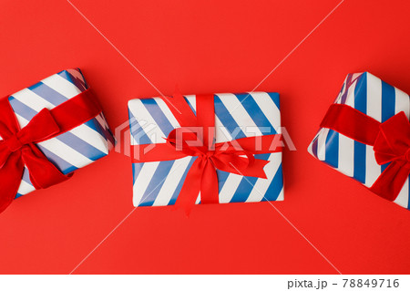 Blue and white stripe gift boxes with red bows on classic red background in the national colors of America, Russia, France or England, the concept of Independence Day, a national holiday, sale Blue and white stripe gift boxes with red bows on classic red background in the national colors of America, Russia, France or England, the concept of Independence Day, a national holiday, sale 78849716