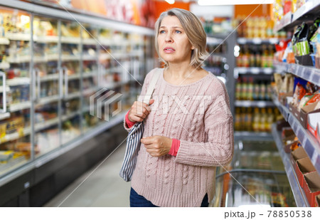 Thoughtful mature woman among shelves in grocery shop Thoughtful mature woman among shelves in grocery shop 78850538