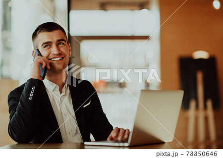 Happy business man sitting at cafeteria with laptop and smartphone 78850646
