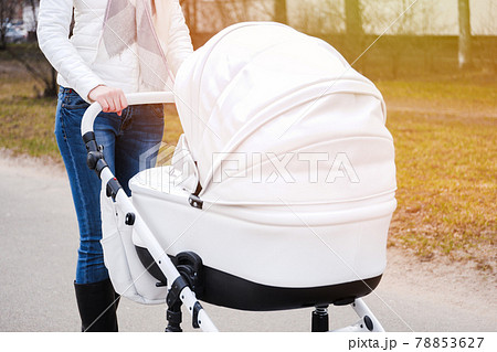 Woman strolling with baby-carriage on the street. Woman strolling with baby-carriage on the street. 78853627