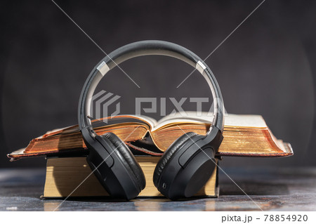 Headphones lying next to old books. Audiobook Concept Headphones lying next to old books. Audiobook Concept 78854920