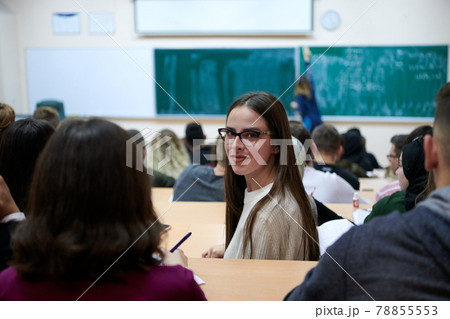 girl sitting in an amphitheater and talking to her colleagues 78855553