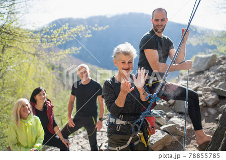 Group of seniors with instructor using chalk before climbing rocks outdoors in nature, active lifestyle. Group of seniors with instructor using chalk before climbing rocks outdoors in nature, active lifestyle. 78855785