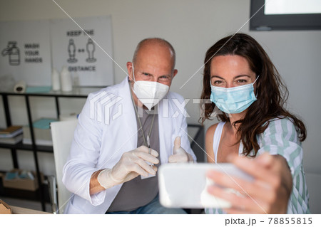 Happy young woman taking selfie with doctor, covid-9 vaccination concept. 78855815