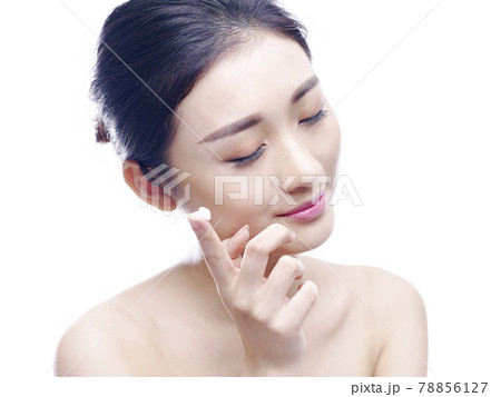 young asian woman applying lotion or cream to face, isolated on white background 78856127