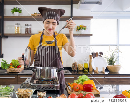The maid is doing the meat stew in a modern kitchen. 78856368