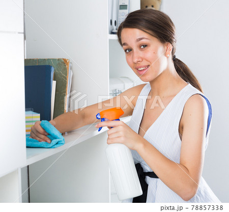 Female teenager is cleaning dust from shelves Female teenager is cleaning dust from shelves 78857338