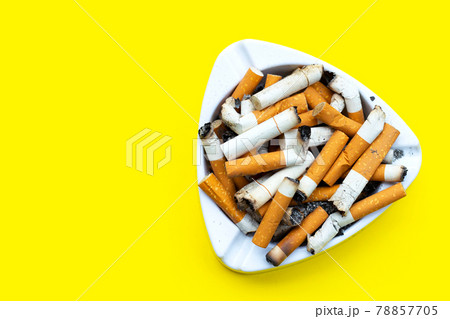 Ashtray and cigarettes on orange background. Ashtray and cigarettes on orange background. 78857705