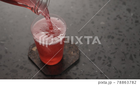 man pour pink drink with ice in tumbler glass 78863782