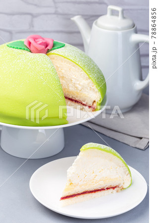 Slice of traditional Swedish dessert Princess cake with green marzipan cover and pink rose decoration, on gray background, vertical 78864856