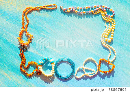 A set of natural jewelry. Space for the text. Coral amber pearl and bone jewelry on a blue background. Top view. A set of natural jewelry. Space for the text. Coral amber pearl and bone jewelry on a blue background. Top view. 78867695