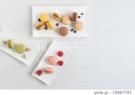 Variety of french macaroons with raspberry, coffee and pistachio on a plate on white wooden table. 78867795
