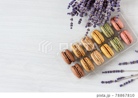Multi colored french macaroons in a box top view on white wooden background. Multi colored french macaroons in a box top view on white wooden background. 78867810