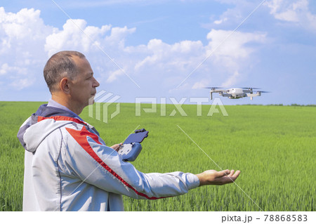 aerial photography of agricultural crops . a man with a quadrocopter on the background of a field and a blue sky 78868583