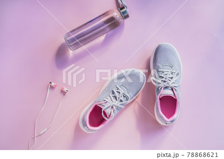 Top view sneakers, earphones and glass water bottle on a pink background. Set for running and sports activities. Healthy and active lifestyle. Online workout. Flat lay. Copy space. Top view sneakers, earphones and glass water bottle on a pink background. Set for running and sports activities. Healthy and active lifestyle. Online workout. Flat lay. Copy space. 78868621