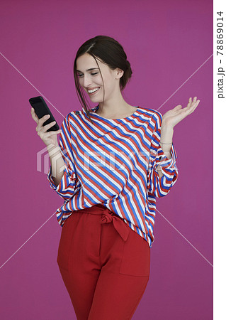Portrait of young girl with happy face while using smartphone isolated on pink background 78869014
