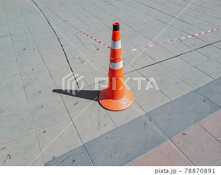 Plastic traffic sign in the shape of a cone on a tile pavement Plastic traffic sign in the shape of a cone on a tile pavement 78870891