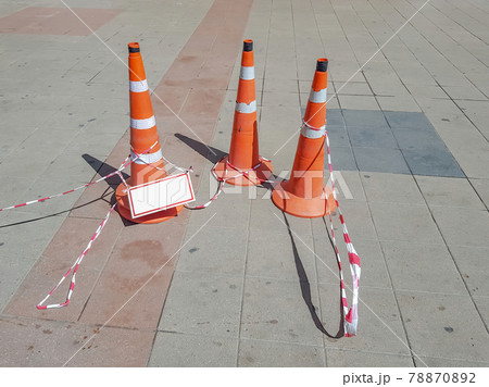 Plastic traffic sign in the shape of a cone on a tile pavement 78870892