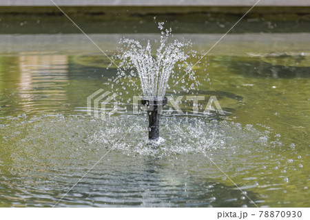 Small fountain in a pond in a summer sunny park 78870930