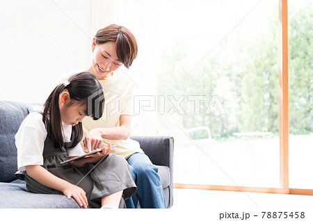 オンライン学習する女の子の隣でサポートする母親 78875458