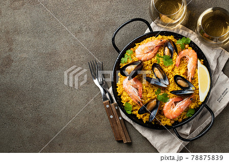 Traditional spanish seafood paella in pan with chickpeas, shrimps, mussels, squid on brown concrete background. Top view with copy space 78875839