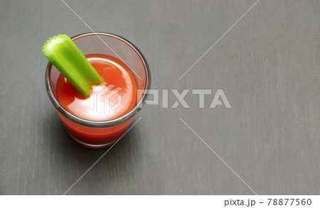 tomato juice in a glass with celery stick on gray wooden background 78877560