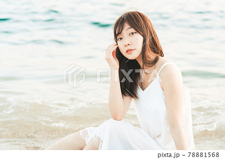 海辺に座るワンピースの女性 の写真素材